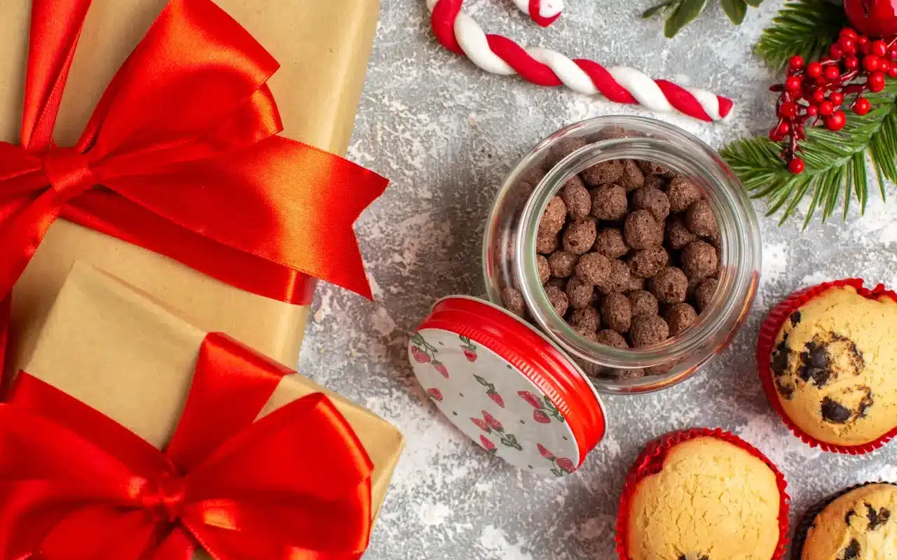 Vue rapprochée de délicieux petits cupcakes et du chocolat dans un pot en verre et des branches de sapin à côté